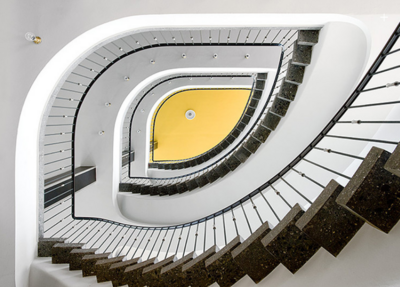 Blick aufwärts in ein modernistisches Treppenhaus mit geschwungenen Geländern